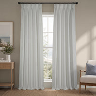 Light gray curtains hanging in a room with a window, chair, and side table.