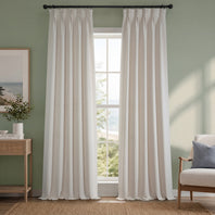 White curtains hanging in a room with a window, light green walls, and a piece of furniture.
