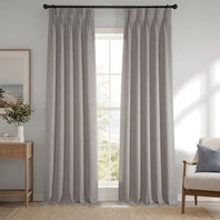 Gray curtains hanging in a room with a window, side table, and chair.