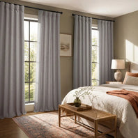 Bedroom with gray curtains, a bed, and a lamp.
