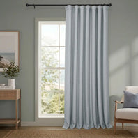 Light blue curtain hanging in a room with a window and furniture.