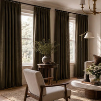 Living room with large windows, dark curtains, and a cozy atmosphere.