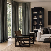 Modern living room with a white sofa, wooden armchair, and bookshelf.