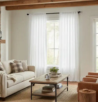 Living room with a beige sofa, wooden coffee table, and white curtains.