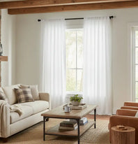 Living room with a beige sofa, wooden coffee table, and white curtains.