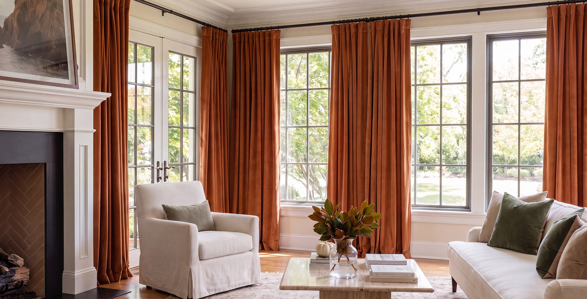Mauve velvet curtains frame tall arched windows in an elegant bedroom with soft neutral furnishings and blush accents.