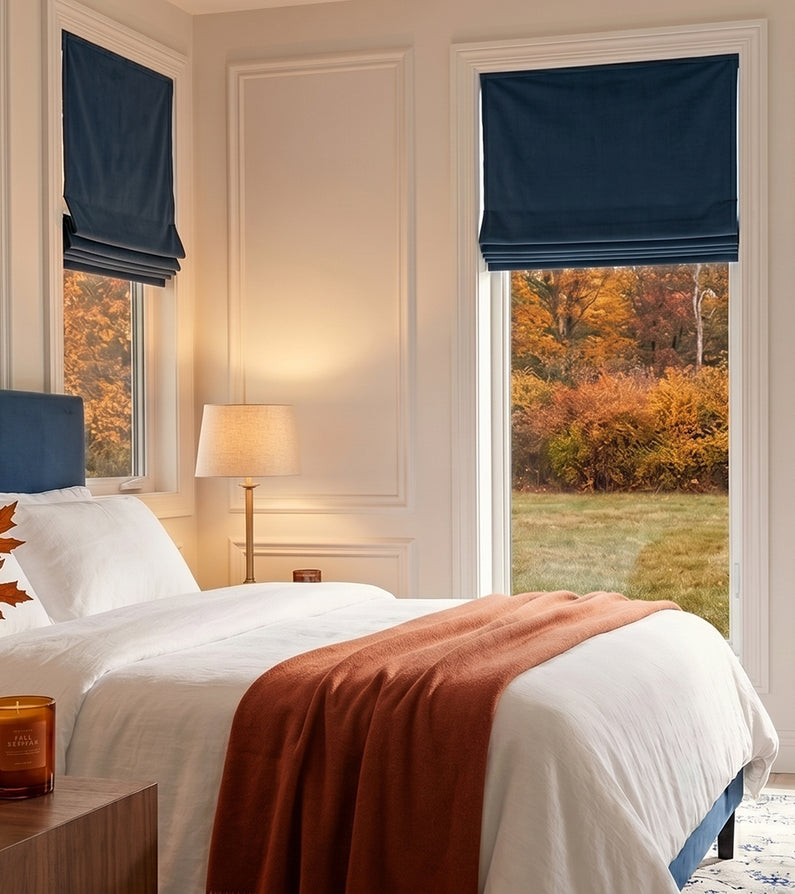 Avalon Blue: Deep navy velvet Roman shades frame bedroom windows, complementing crisp white bedding and warm autumn accents.