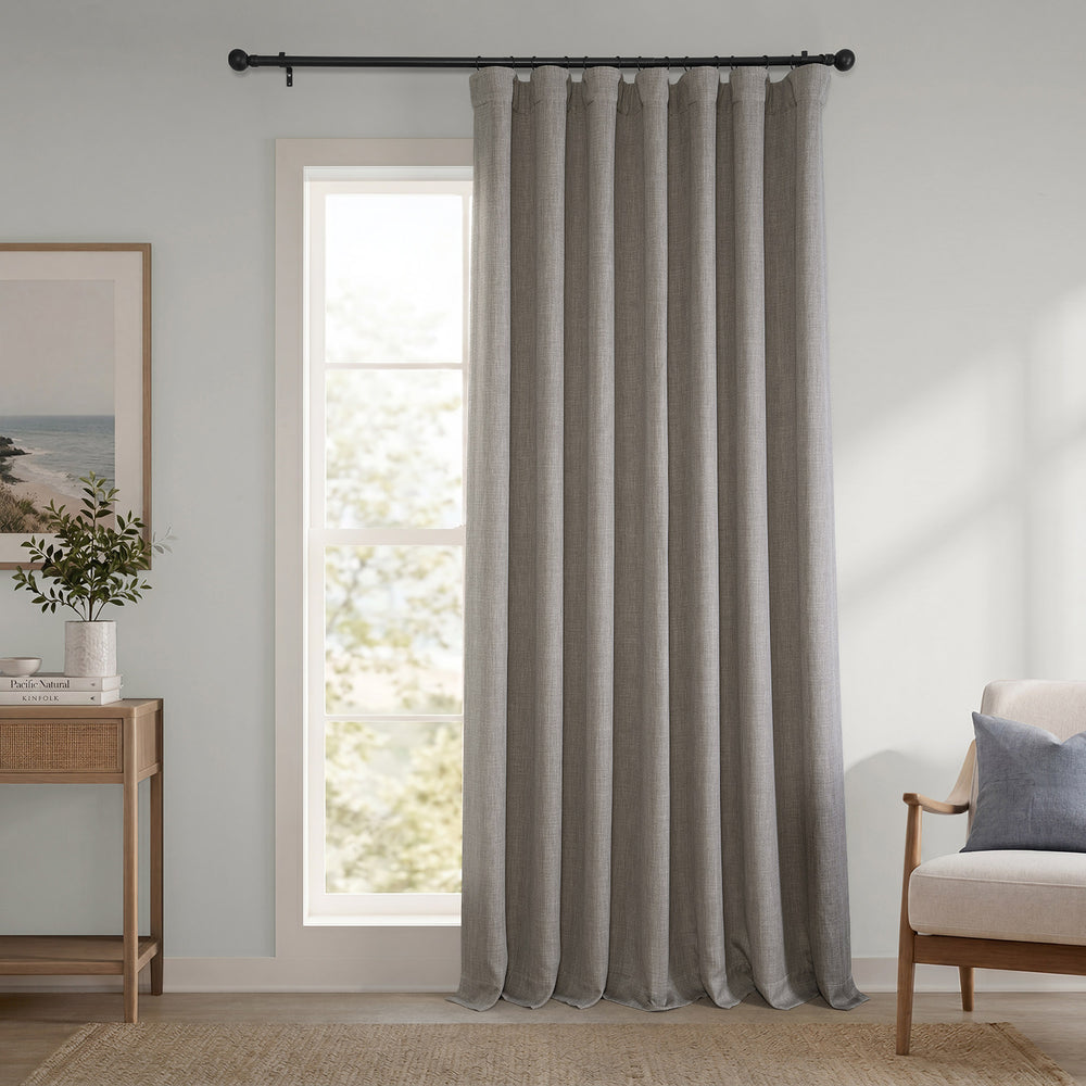 Gray curtain hanging in a room with a window, side table, and chair.