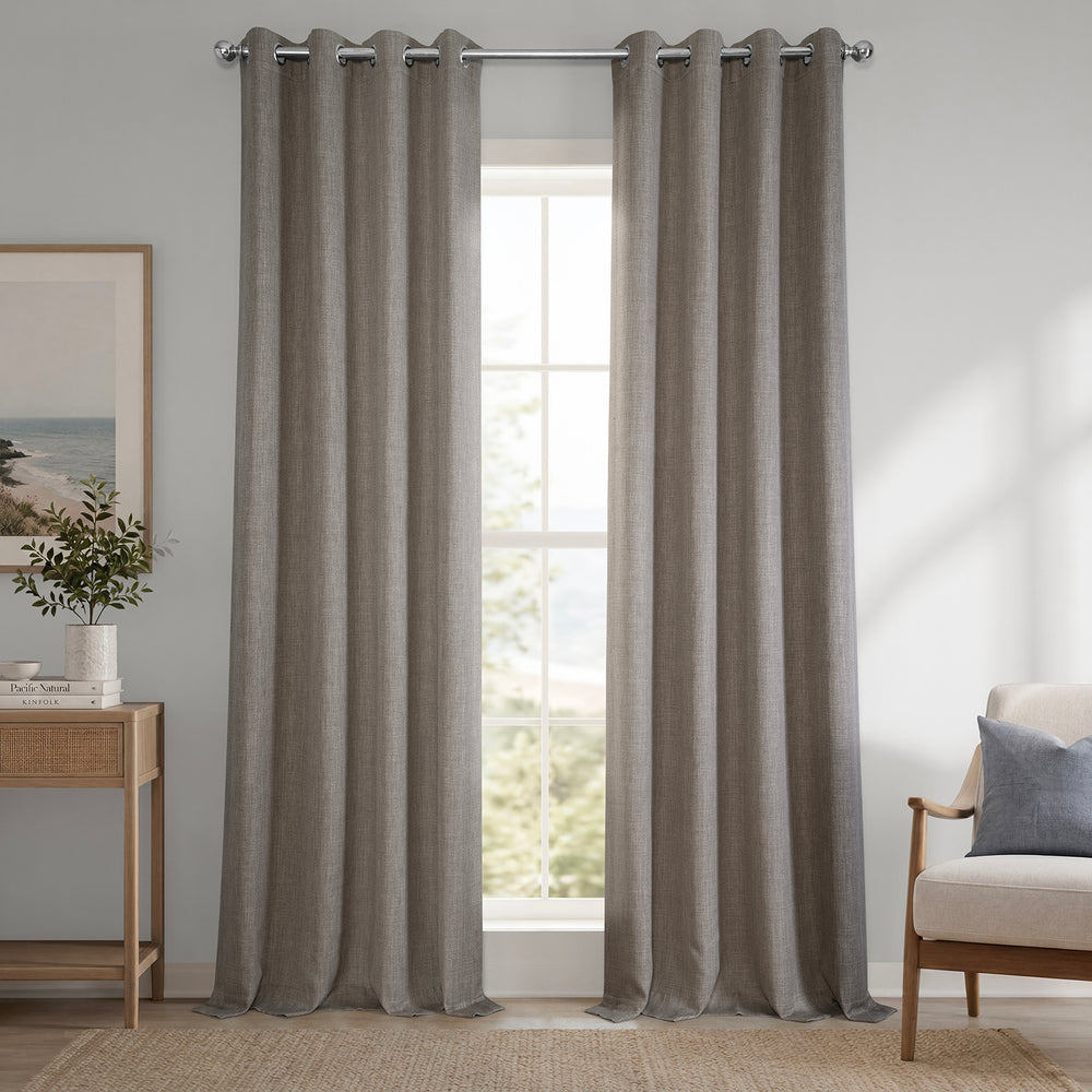 Gray curtains hanging in a room with a window, chair, and side table.