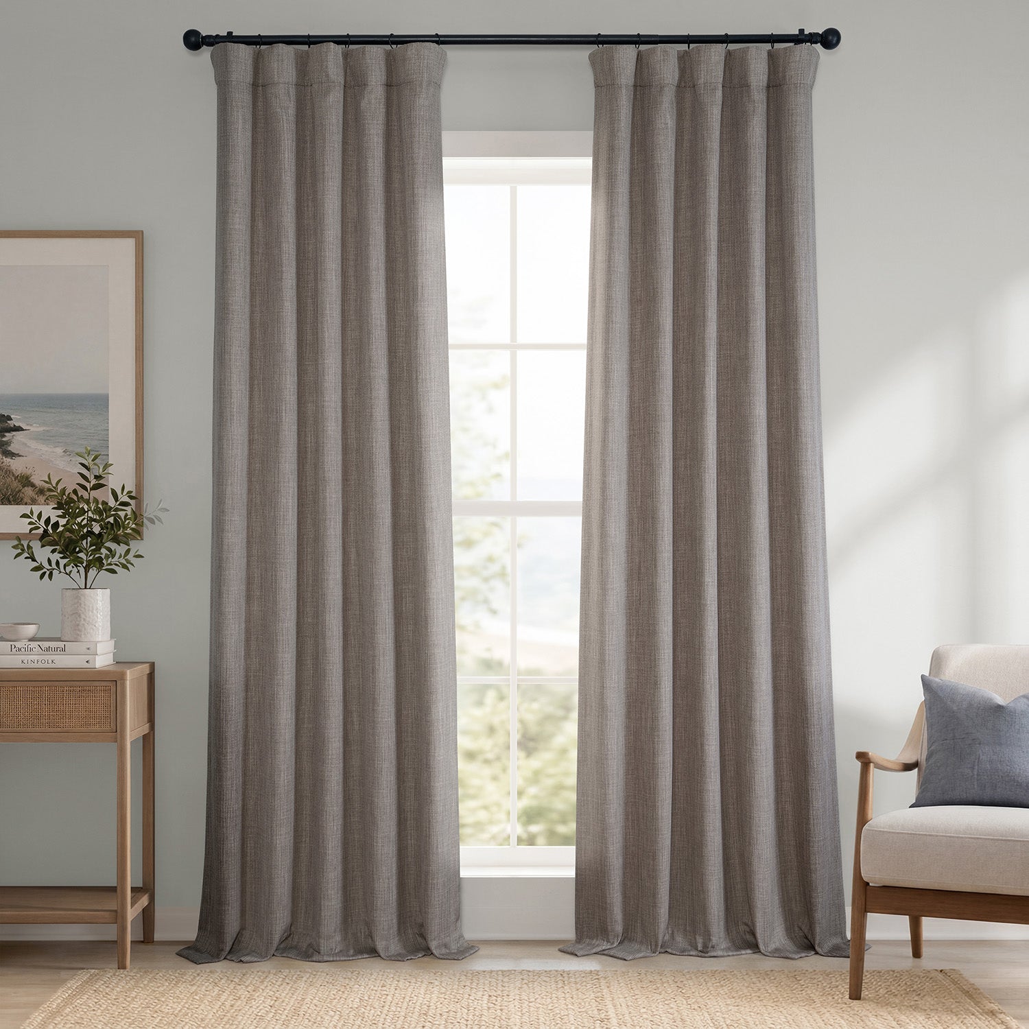 Pair of gray curtains hanging in a window with a chair and side table in the foreground.