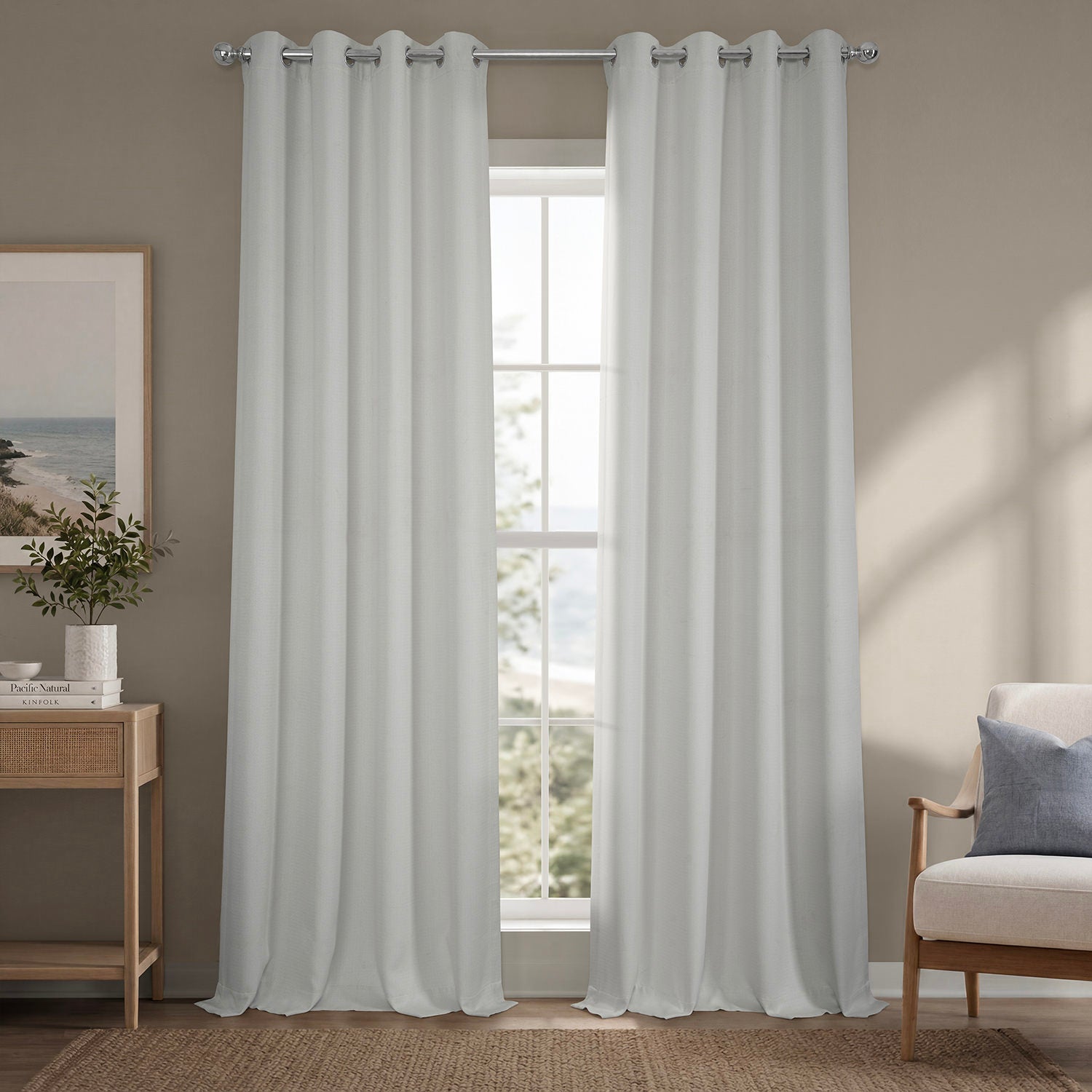 Sheer white curtains hanging in a room with a window, side table, and chair.