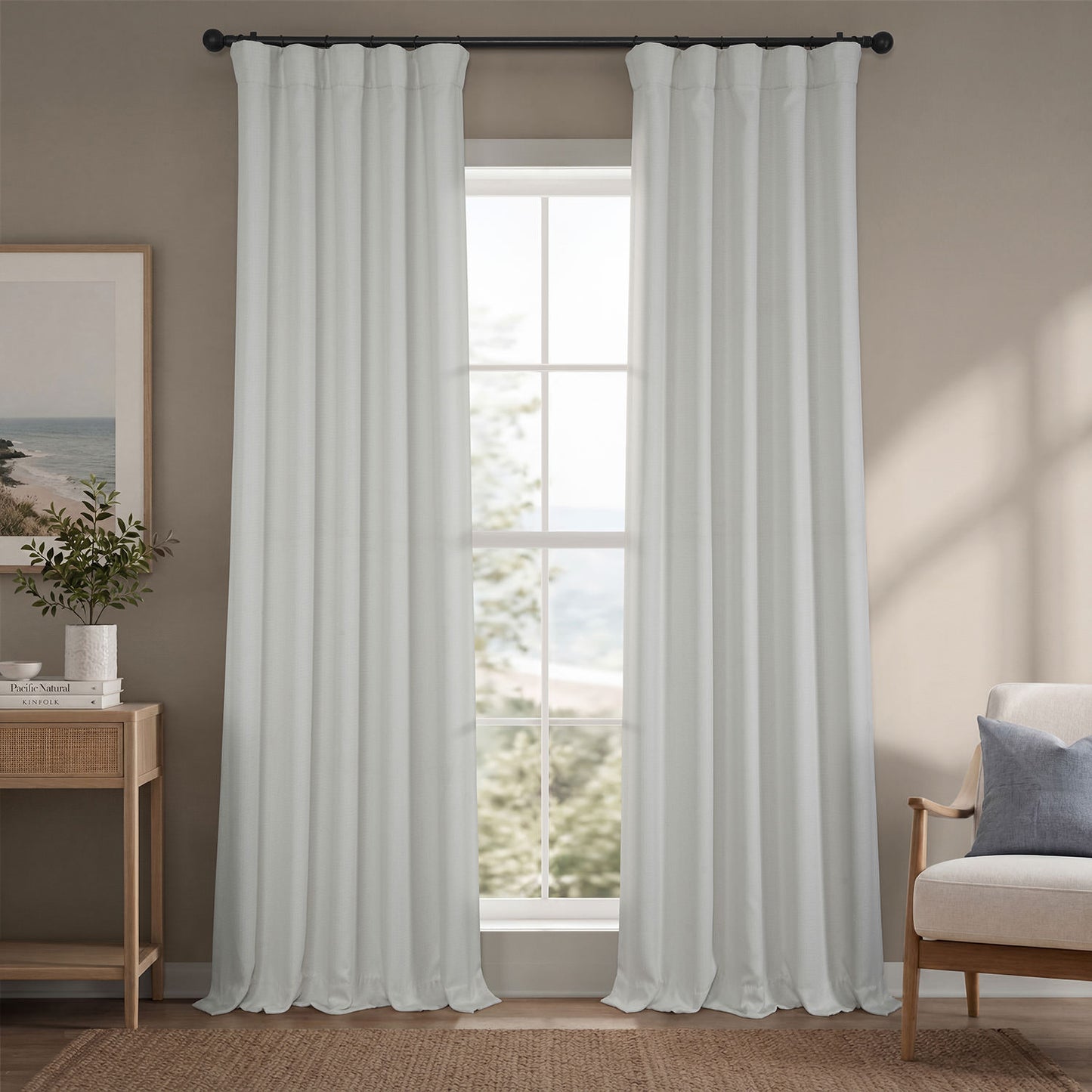White curtains hanging in a room with a window, side table, and chair.