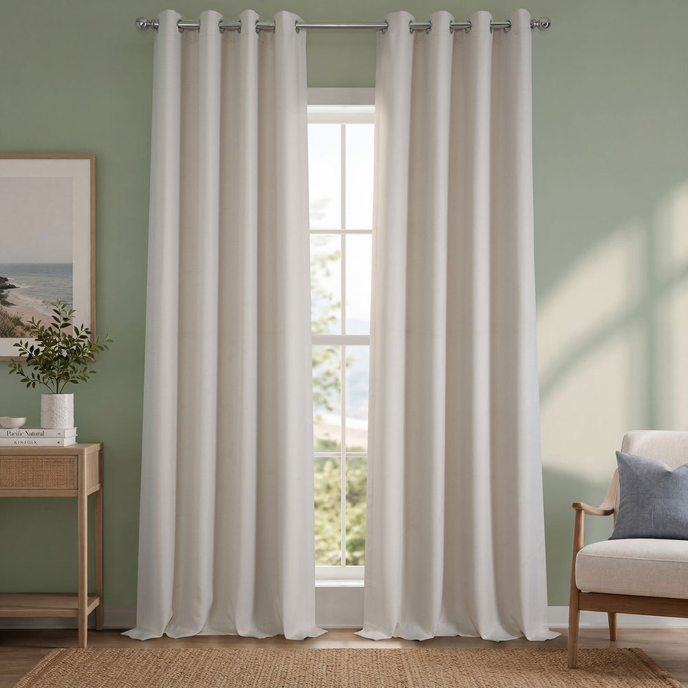 White curtains hanging in a room with a green wall, a window, a side table with a plant, and a chair with a pillow.