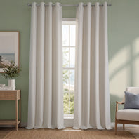 White curtains hanging in a room with a green wall, a window, a side table with a plant, and a chair with a pillow.