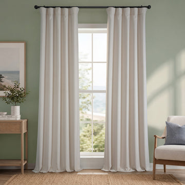 Striped curtains in a room with a window, chair, and side table.