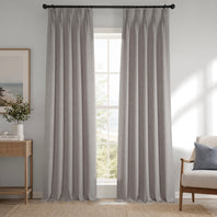 Gray curtains hanging in a room with a window, side table, and chair.