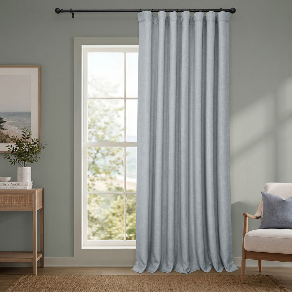 Light blue curtain hanging in a room with a window and furniture.