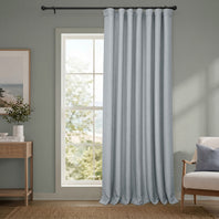 Light blue curtain hanging in a room with a window and furniture.