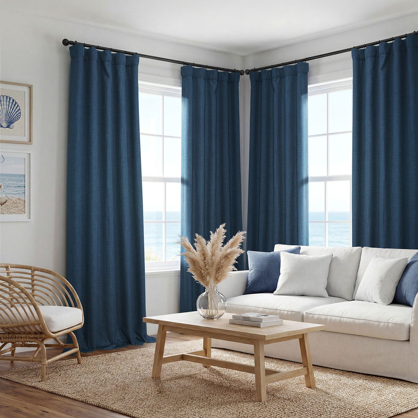 A set of deep navy blue grommet curtains hanging on a black rod in a bright, modern living room with a white sofa, wooden coffee table, and ocean view windows.