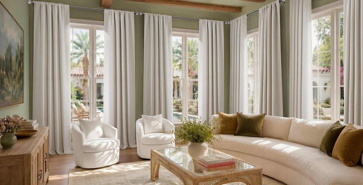 Bright living room featuring floor-to-ceiling ivory textured faux linen curtains that soften natural light, creating a warm, airy atmosphere with neutral furnishings, green accent walls, and views of a lush outdoor patio.