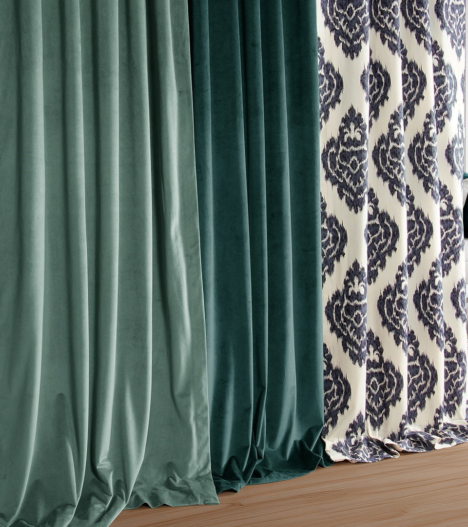 Collection of custom curtain fabrics in coastal blue tones, featuring velvet, textured solids, and navy damask patterns displayed in elegant floor-length drapery panels.