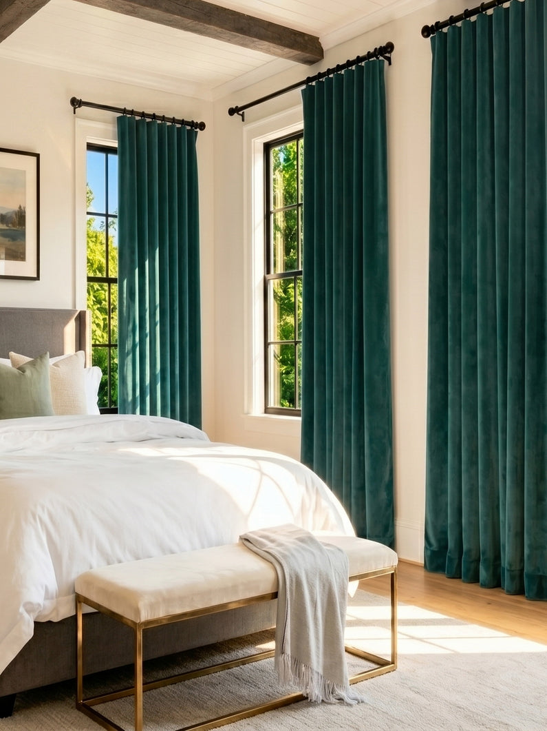 Deep sea teal curtains frame tall bedroom windows, adding rich color and an elegant, tailored look to the bright space.