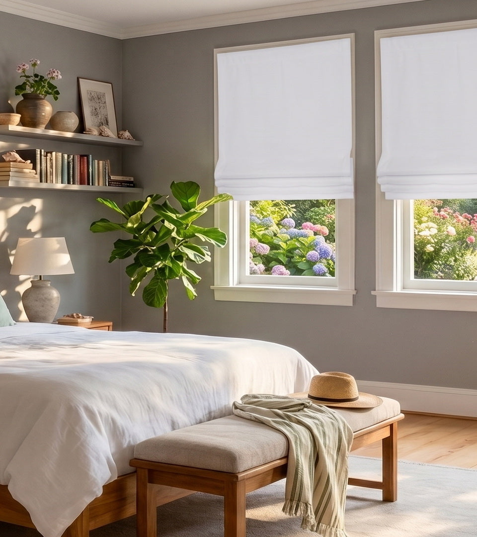 Bright white Roman shades create a clean, timeless look in this inviting living room, softly filtering natural light while maintaining privacy. Their crisp, tailored design complements the cool gray walls, neutral furnishings, and warm wood accents, bringing a fresh, airy feel to the space.