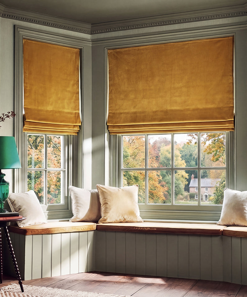 Spiced Rum Heritage Plush: Golden spiced rum Roman shades bring warm, sophisticated color to a sunlit neutral bedroom.