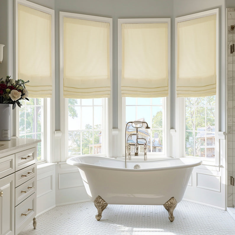 Gravity Italian Faux Linen: Soft ivory Roman shades filter natural light across four tall bathroom windows surrounding a freestanding tub.