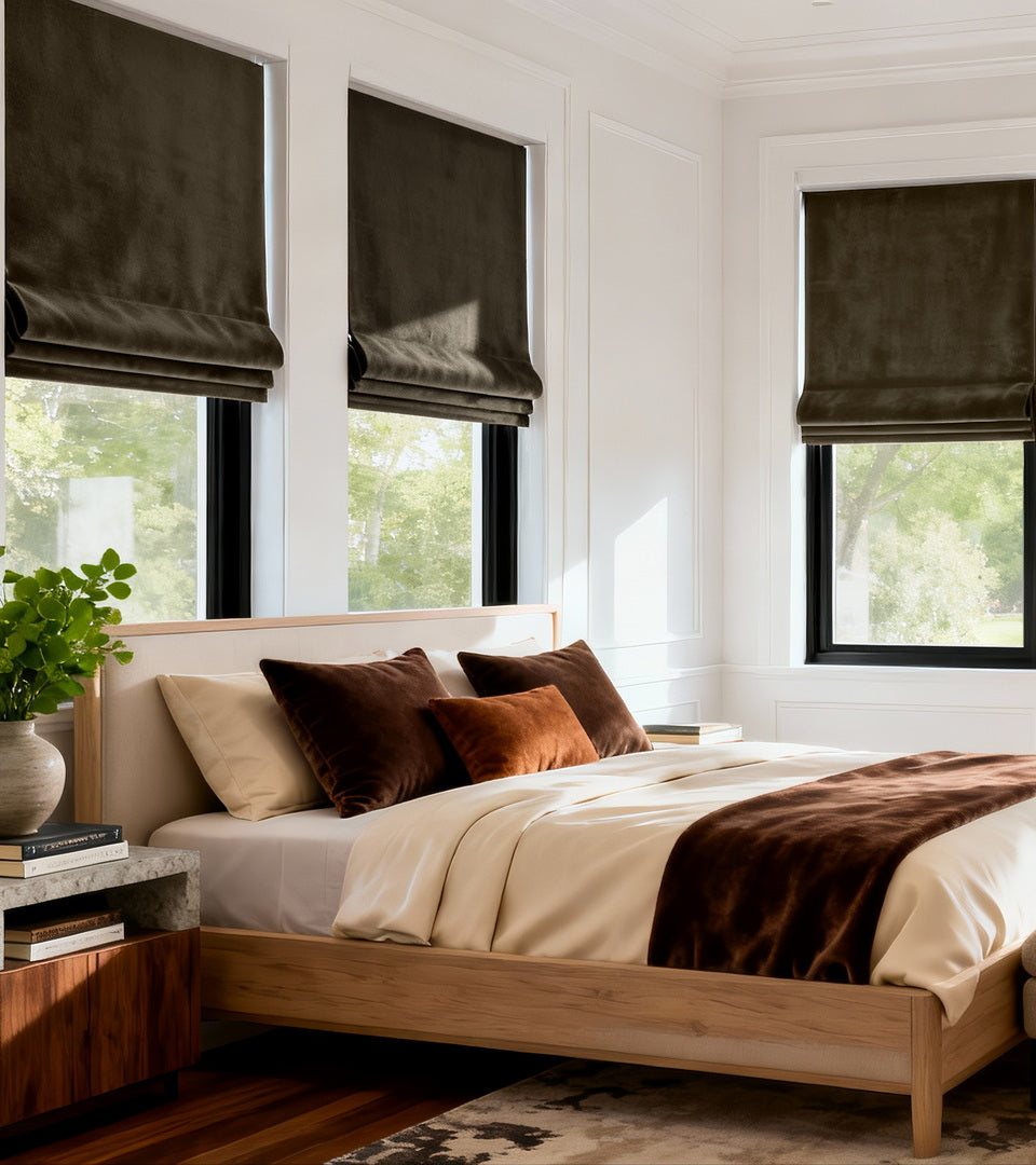 Rich espresso Roman shades add depth and luxurious texture to this modern bedroom. Their tailored silhouette provides privacy and light control while the warm brown hue beautifully complements the natural wood furnishings, crisp white walls, and layered neutral bedding for a cozy, sophisticated retreat.