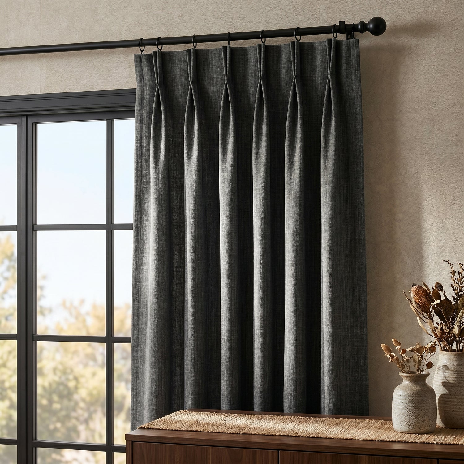 Dark pleated curtains hanging from decorative rod highlighting tailored designer styling.