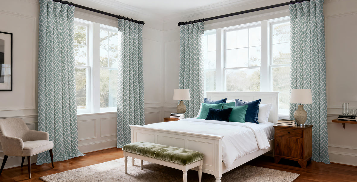 Soft aqua geometric printed curtains bring a fresh, coastal-inspired feel to this bright bedroom with their crisp white background and elegant interwoven pattern. The cool blue-green tones pair beautifully with the white furnishings and rich navy accent pillows, adding subtle color, texture, and timeless style while filling the room with light and tranquility.