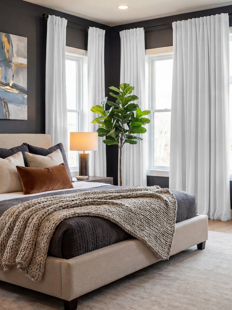 Mission White Linen: Crisp white linen curtains brighten a modern bedroom with dark walls, layered neutral bedding, and natural greenery.
