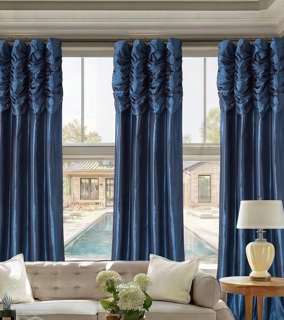 Royal Blue curtains framing a large window in a sitting room with a glass coffee table and upholstered chair.