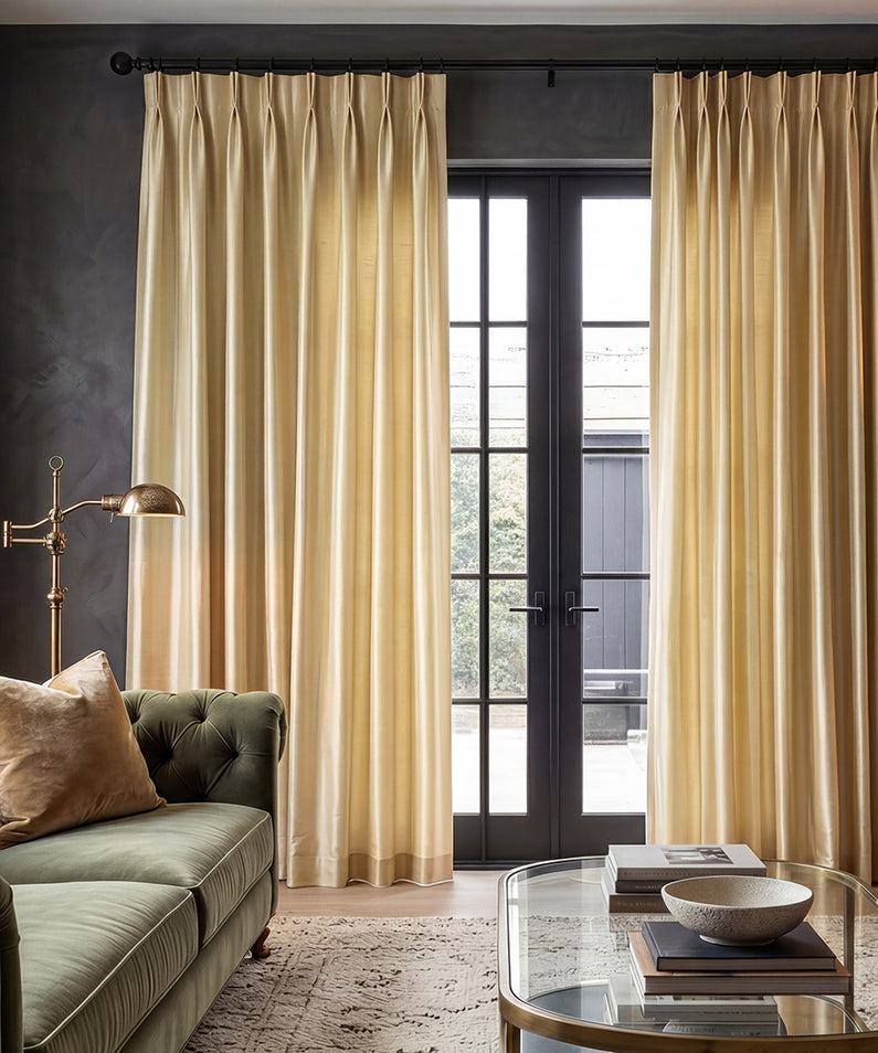 White pinch pleat curtains frame a tall window with a city view, creating an elegant, tailored look in a modern interior.