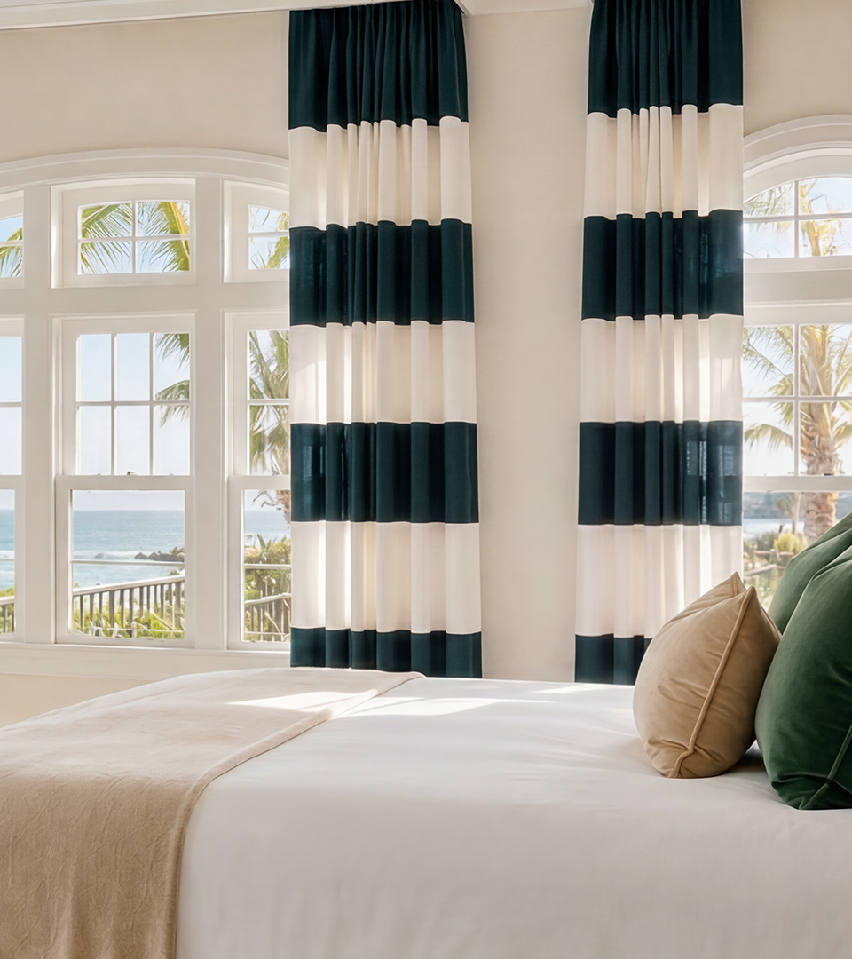 Black and white striped bedroom curtains surrounding bright windows in a coastal-inspired bedroom.