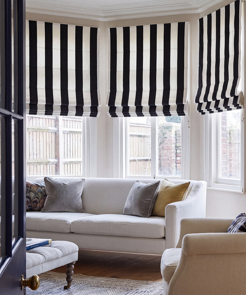 Cabana Black Striped Printed Cotton: Black and white striped Roman shades create a bold, graphic statement in a modern bedroom.
