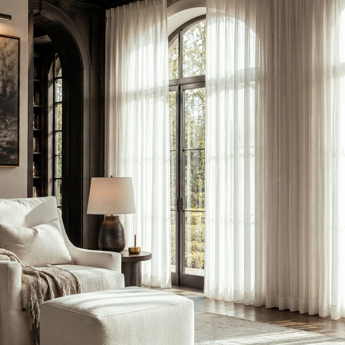 Living room with white sofa, lamp, and large windows with white curtains.