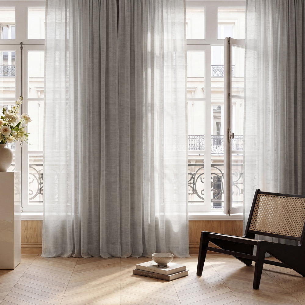 Sheer curtains in a room with a chair and decorative items.