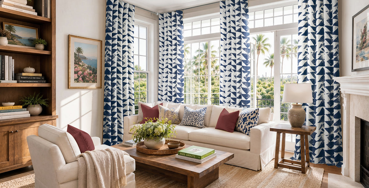 Bold indigo-and-white patterned curtains create a fresh statement in a bright, coastal-inspired living room.