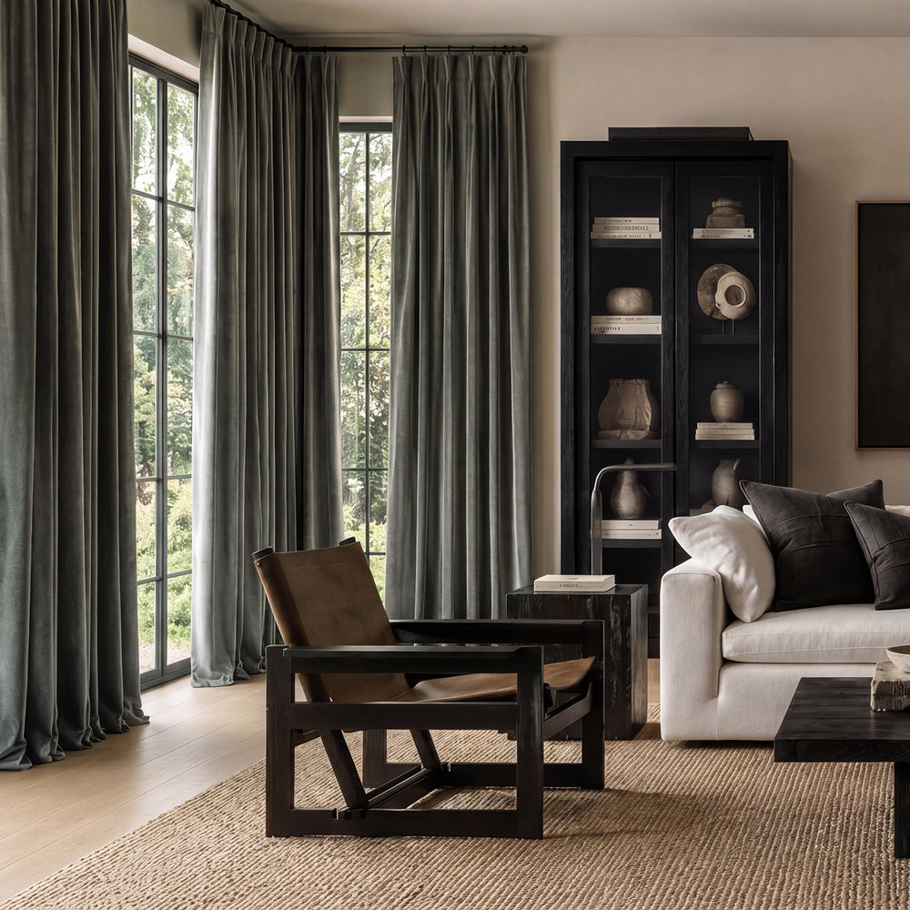 Modern living room with a white sofa, wooden armchair, and bookshelf.