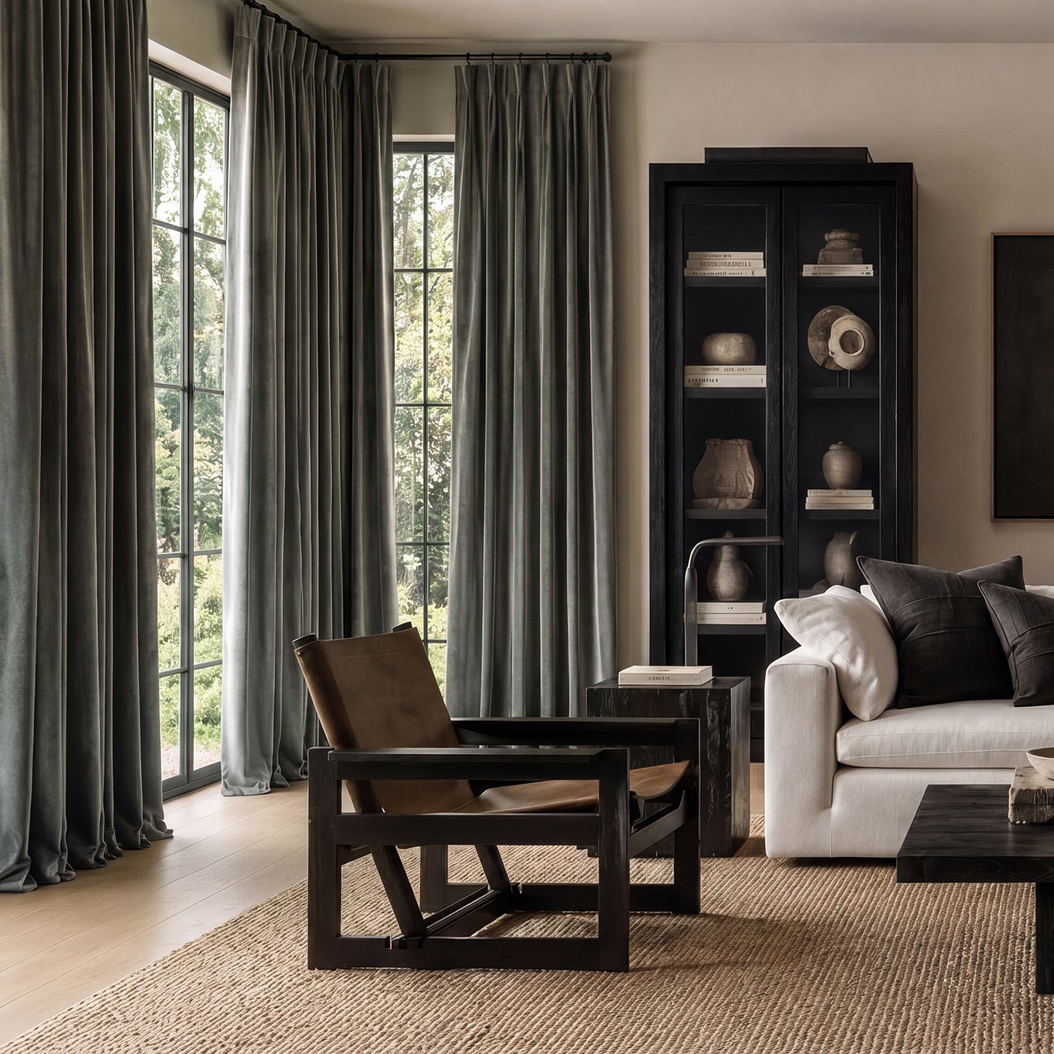 Modern living room with a white sofa, wooden armchair, and bookshelf.