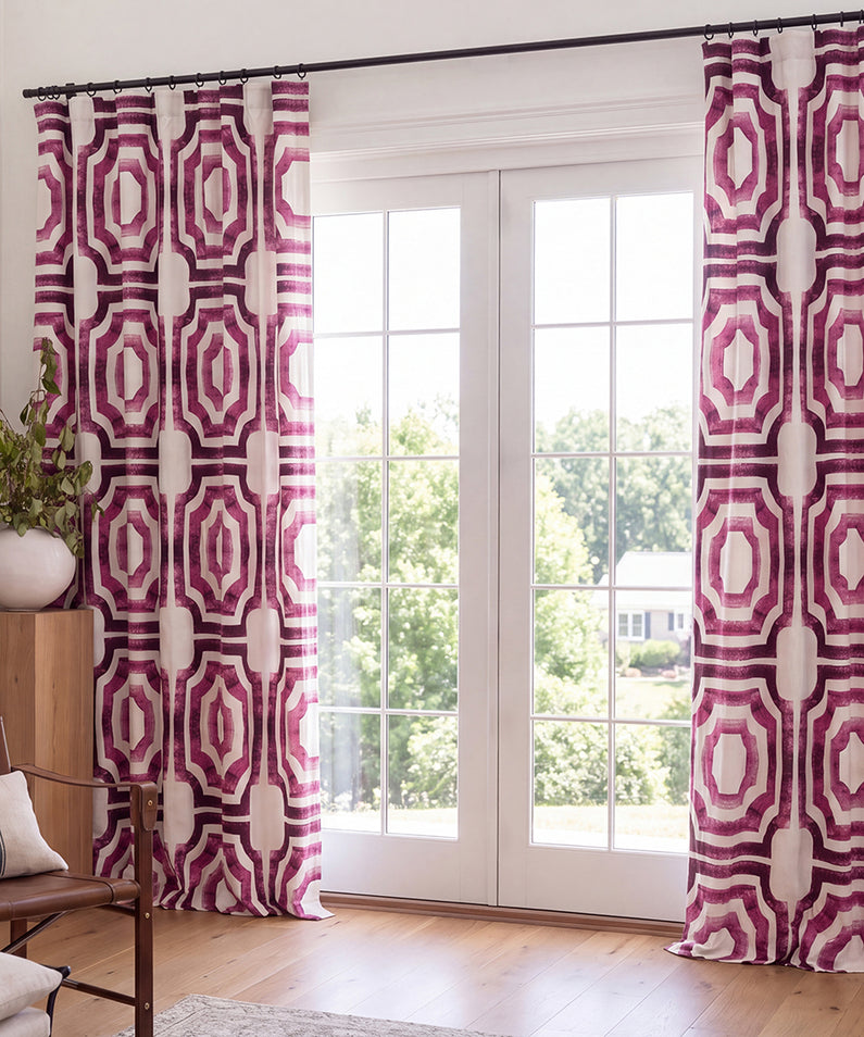 Black-and-white geometric patterned curtains hang from decorative rings, adding a modern statement to a bright, neutral living room.